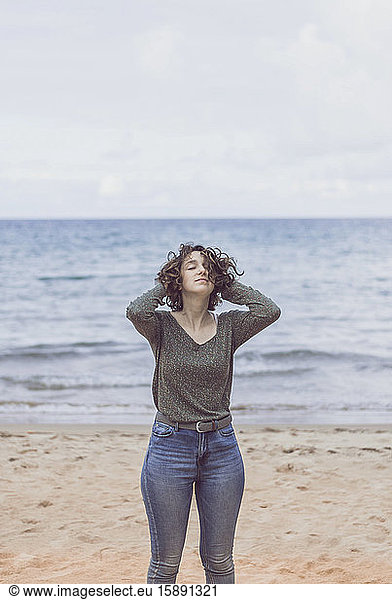 Junge Frau genießt den Wind am Strand