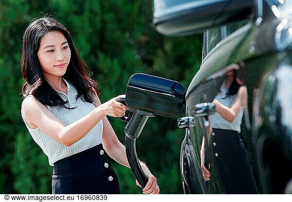 Junge Frau hält eine Waffe für Autobatterie