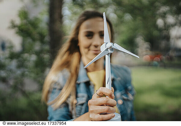 Junge Frau hält Modell einer Windkraftanlage