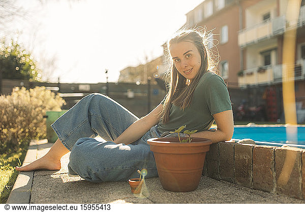 Junge Frau im Garten mit Sämling im Blumentopf