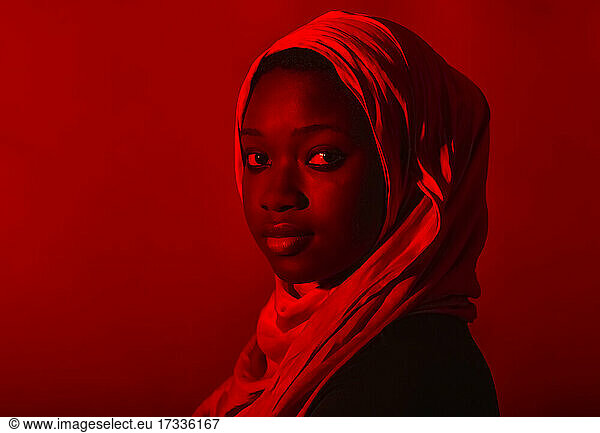 Junge Frau im Hidschab starrt vor rotem Hintergrund