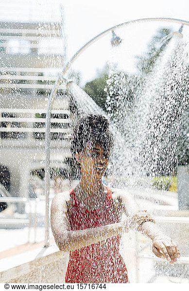 Junge Frau im roten Badeanzug duscht im Freien