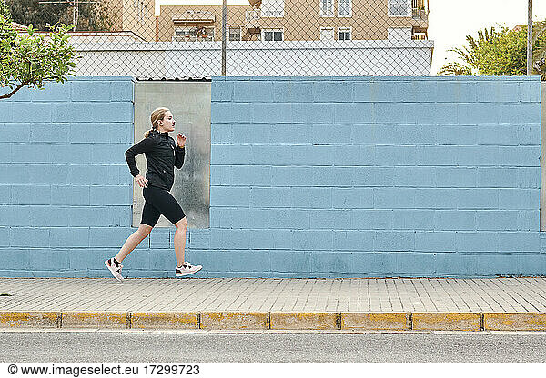 Junge Frau in Sportkleidung läuft durch die Stadt