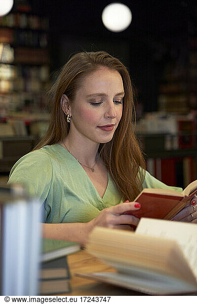 Junge Frau konzentriert sich beim Lesen eines Buches in einer Bibliothek