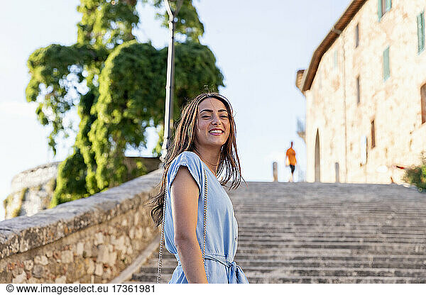 Junge Frau lächelt  während sie auf einer Treppe steht