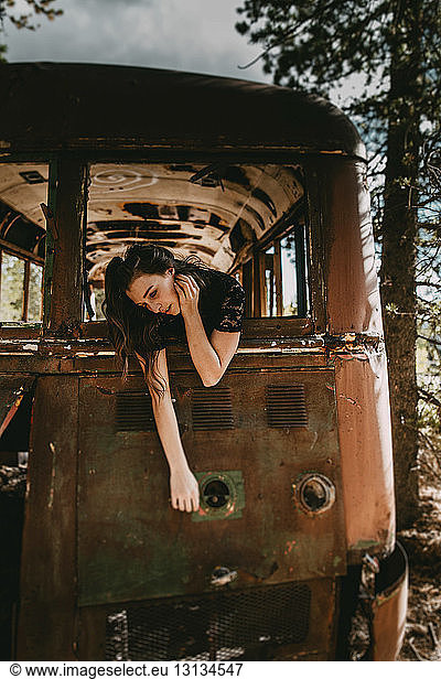 Junge Frau lehnt sich aus dem Fenster eines verlassenen Busses