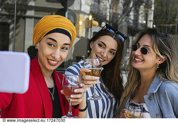 Junge Frau macht Selfie mit Freundinnen bei einem Drink