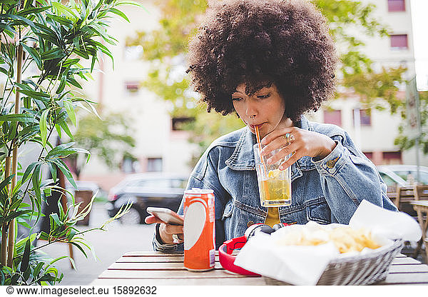 Junge Frau mit Afro-Frisur in einem Straßencafé in der Stadt