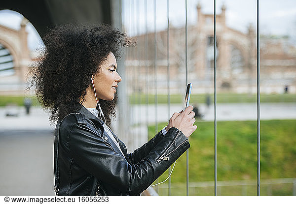 Junge Frau mit Afrofrisur beim Fotografieren mit Smartphone