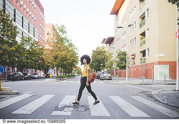 Junge Frau mit Afrofrisur geht in der Stadt spazieren