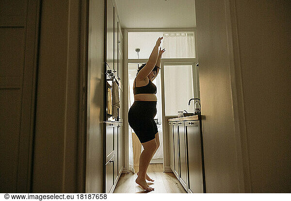 Junge Frau mit erhobenen Armen genießt den Tanz in der Küche zu Hause