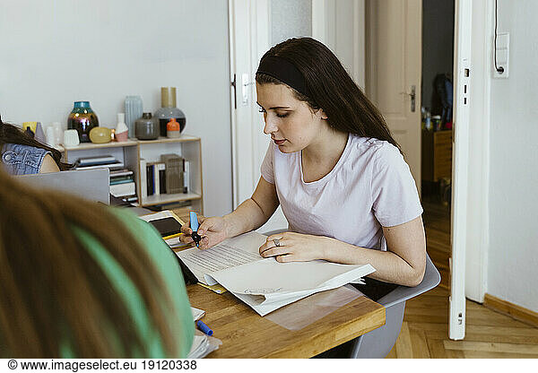 Junge Frau mit Filzstift studiert am Esstisch