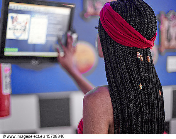 Junge Frau mit geflochtener Frisur  die die Bestellungen auf einem Bildschirm überprüft