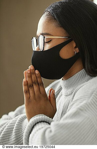 Junge Frau mit Gesichtsmaske beim Gebet
