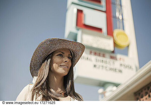 Junge Frau mit Hut  die lächelnd in der Stadt steht