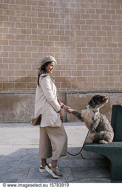 Junge Frau mit ihrem Hund in der Stadt beim Pfötchengeben