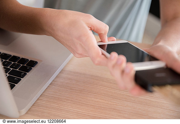 Junge Frau mit Smartphone am Schreibtisch  Nahaufnahme der Hände