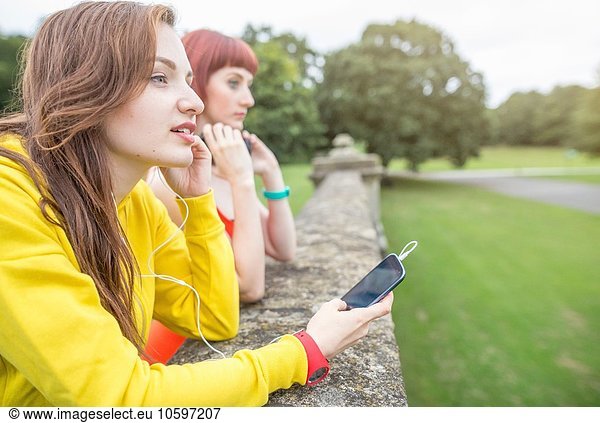 Junge Frau mit Smartphone an der Steinwand lehnend