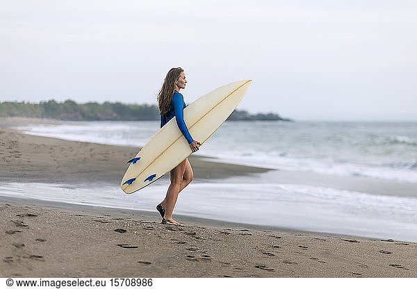 Junge Frau mit Surfbrett am Strand  Strand von Kedungu  Bali  Indonesien