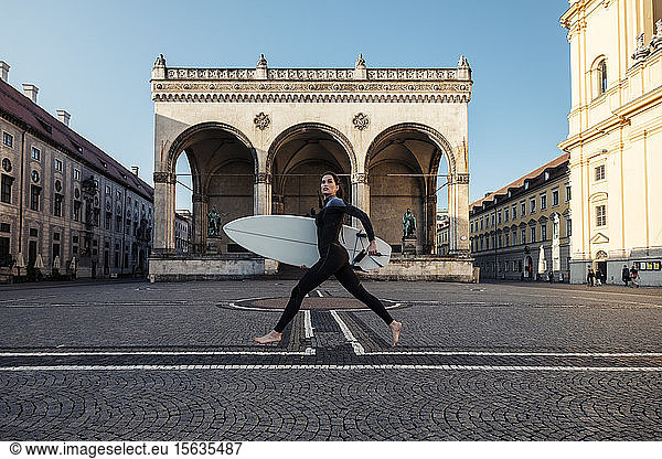 Junge Frau mit Surfbrett auf dem Weg nach Eisbach  München  Deutschland