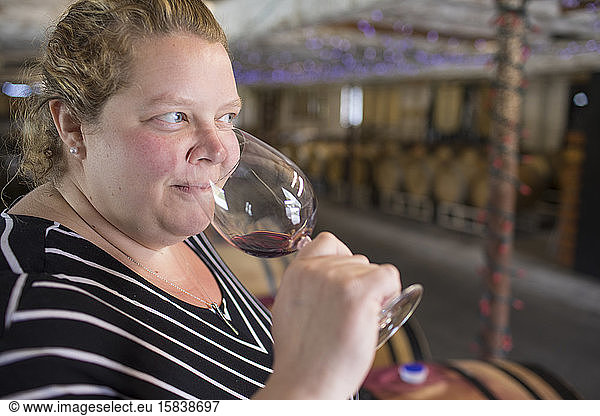Junge Frau riecht Aromen von Rotwein im Weingut.