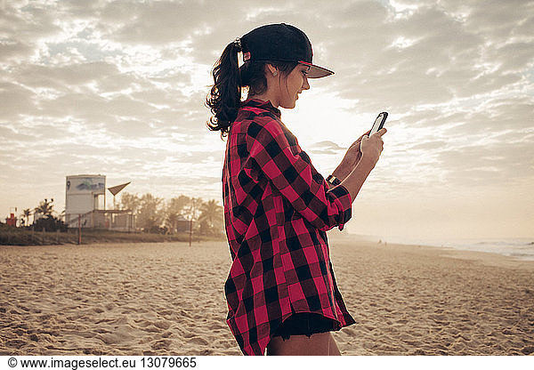Junge Frau schreibt am Strand SMS