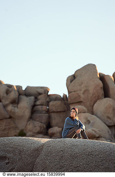 Junge Frau sitzt auf Felsen und grübelt