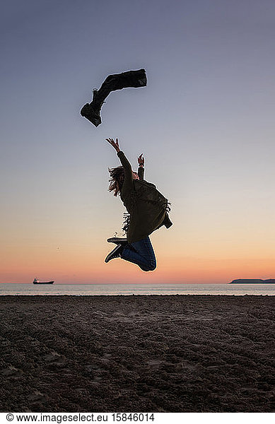 Junge Frau springt bei Sonnenuntergang an den Strand. Lebensstil  Freiheit