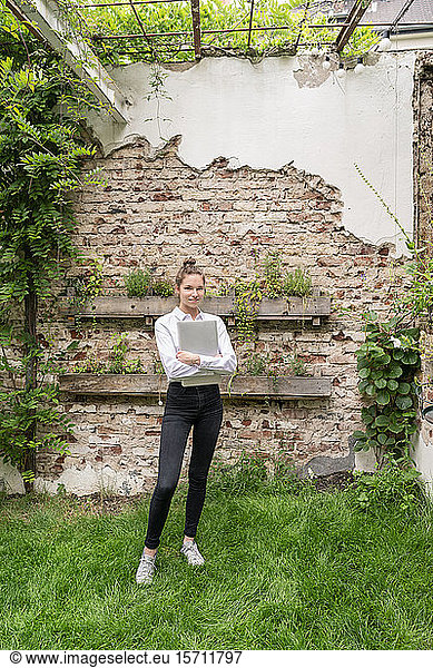 Junge Frau steht im Hinterhof und hält ein digitales Tablet