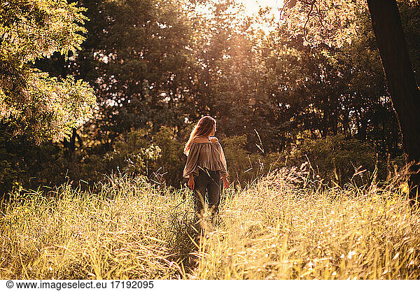 Junge Frau steht im Sommer im Gras im Wald