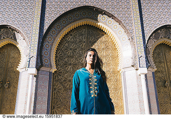 Junge Frau steht in marokkanischer Robe vor traditionellen Archiven  Marokko