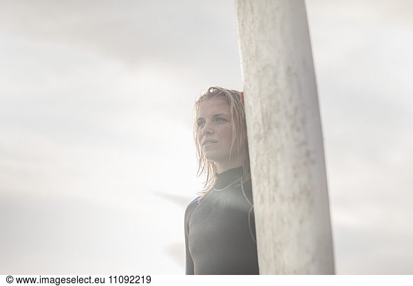 Junge Frau steht neben dem Surfbrett