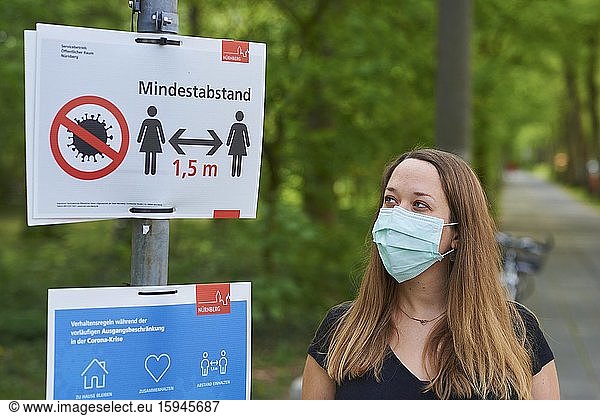 Junge Frau steht vor einem Schild Abstand halten  soziale Distanz  Coronakrise  Bayern  Deutschland  Europa