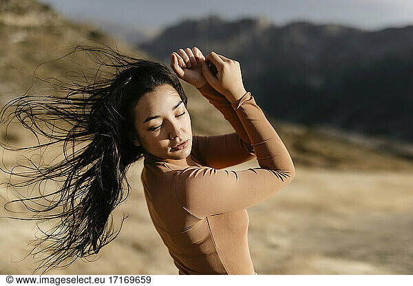 Junge Frau tanzt bei Sonnenuntergang im Wind