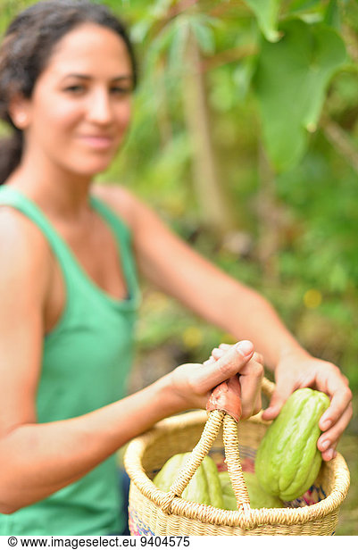 Junge Frau trägt Korb mit frischem Gemüse