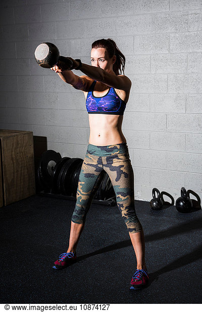 Junge Frau trainiert  Gewichtheber-Hantel im Fitnessstudio