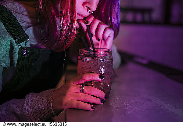 Junge Frau trinkt abends einen Drink