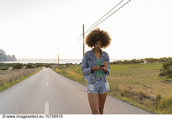 Junge Frau unterwegs mit Smartphone  Ibiza