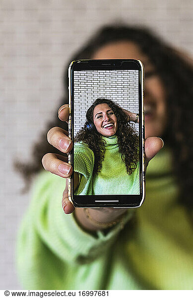 Junge Frau zeigt Foto auf Smartphone