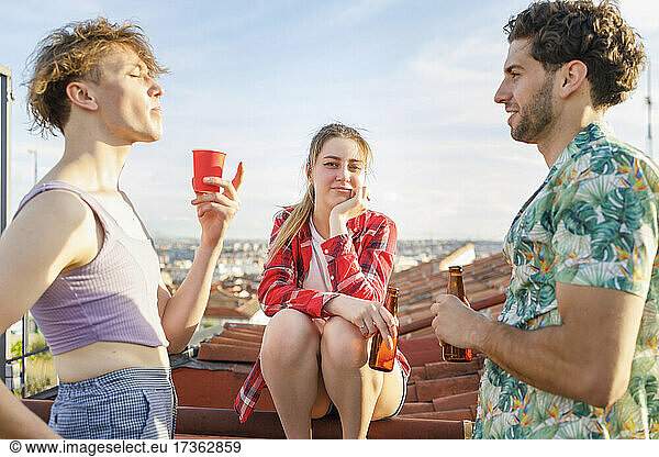Junge Freunde unterhalten sich am Wochenende bei einem Drink auf einem Dach