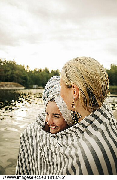Junge Freundinnen mit Handtuch am See im Urlaub