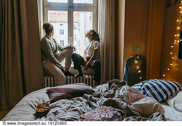 Junge Freundinnen sitzen am Fenster im Schlafzimmer