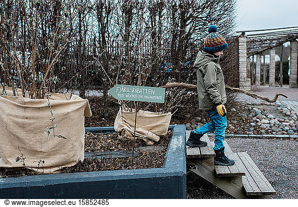 Junge gärtnert im Winter durch einen schwedischen Garten