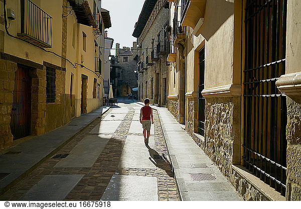 Junge geht in einer Gasse mit alten Häusern in Rubielos de Mora spazieren