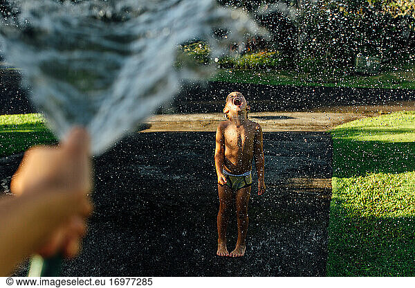 Junge genießt Wasserplätschern in der Sonne
