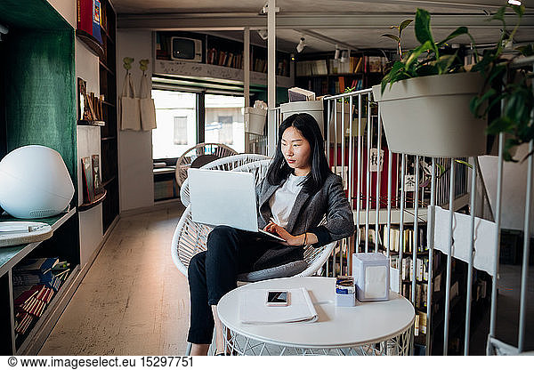 Junge Geschäftsfrau benutzt Laptop im Buchladen