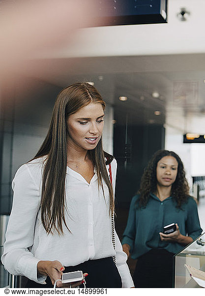 Junge Geschäftsfrau durchläuft Check-in-Prozess am Flughafen