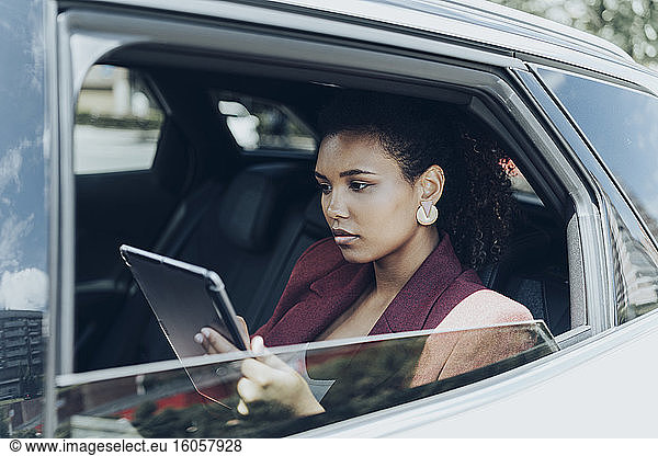 Junge Geschäftsfrau mit digitalem Tablet durch Autofenster gesehen