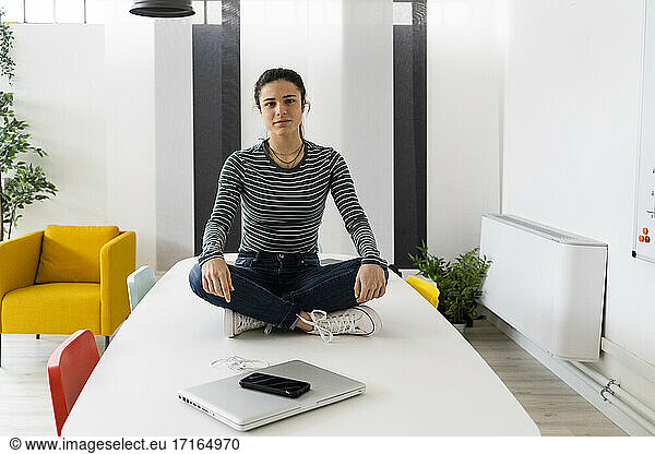 Junge Geschäftsfrau sitzt am Tablet am Arbeitsplatz