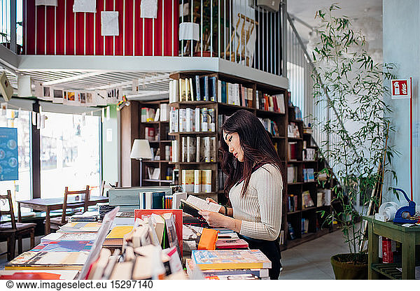 Junge Geschäftsfrau stöbert in Büchern im Buchladen